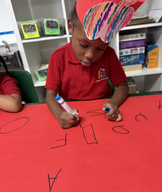 Young learner practicing writing at Leading Learners Academy